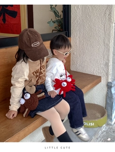 Close-up of children sitting on a bench with cute crochet crab crossbody bags