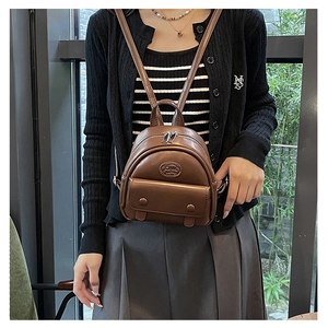 Brown PU leather mini backpack with double zippers and decorative buttons on a model