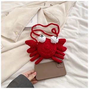 Detail shot of mini crochet crab bag for kids showing small size next to a phone