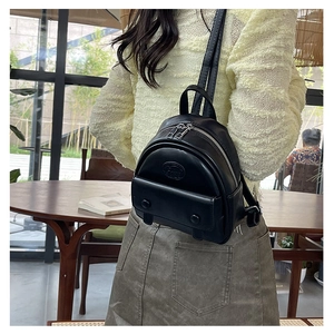 Detail of a black mini leather backpack with silver zippers worn by a model in daily life