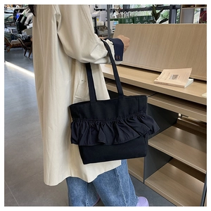 Detail of ruffle trim on a large black canvas tote bag for casual everyday styling