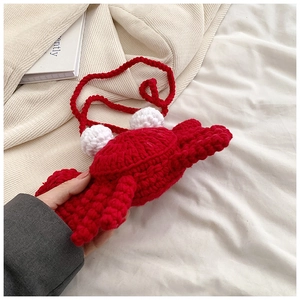 Detail of a handmade red crochet crab shoulder bag for kids held in hand