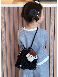 Detail of crochet sheep crossbody bag with knit texture and pearl accent on a child
