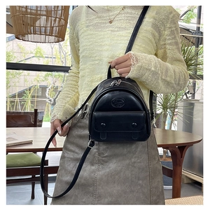 Detail view of a black mini PU leather backpack with silver zippers and a front rivet pocket