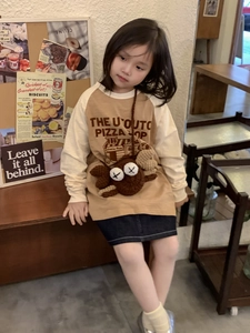 Detail of a brown crochet crossbody bag featuring a cartoon crab design on a child model