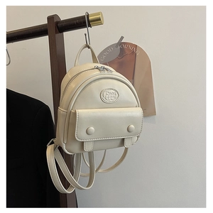 Detail view of mini cream backpack featuring front flap pocket and fashion logo