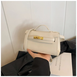 Détail du mini sac bandoulière crème avec fermoir rotatif doré et poignée élégante