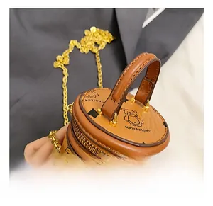 Detail der Mini-Eimertasche mit Ledergriff, goldener Kette und Bärenmuster-Print