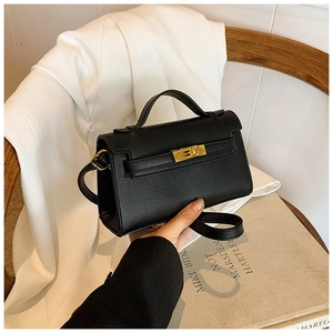 Détail du mini sac à main noir à grain croisé avec boucle dorée au design classique