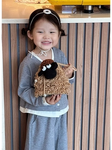 Detail of a brown crochet sheep kid's bag featuring a textured handle and pearl accents