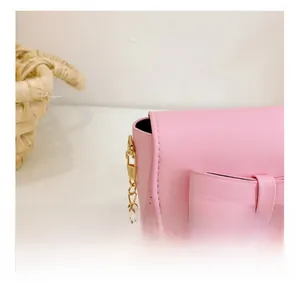 Detailed close-up of precise stitching on pink girl's bow shoulder bag with gold chain
