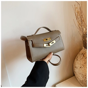 Détail du mini sac à main en cuir taupe avec fermoir rotatif doré et poignée élégante