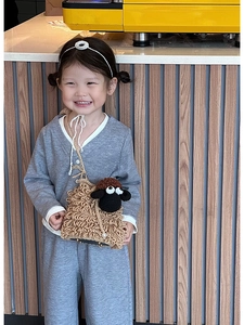 Detail of a cute crochet sheep crossbody bag worn by a child on a minimalist background