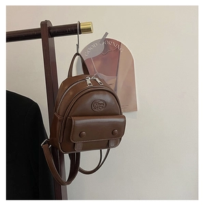 Detail view of a vintage dark brown mini backpack hanging on a wooden hook