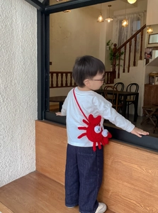 Detail of red crochet crab shoulder bag for kids with unique cross eye design