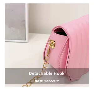 Détail du crochet métallique doré amovible et du cuir matelassé rose sur le sac coquillage