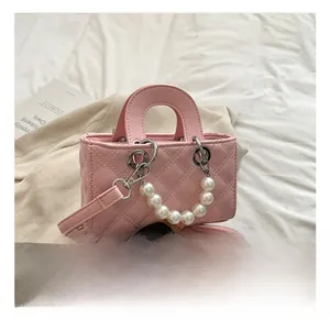 Detail of pink quilted crossbody bag for kids featuring decorative pearl handle strap