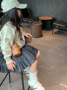 Seitenansicht einer Mini-Zylindertasche aus braunem Leder mit schicker Goldkette