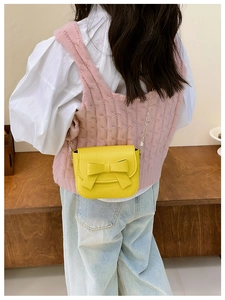 Mini yellow crossbody bag with bow detail and gold chain shown on a child model