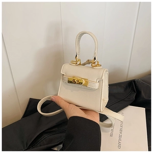 Détail de la texture en cuir croisé beige et du fermoir en métal doré sur le sac