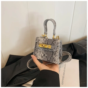 Détail d'un mini sac à main avec texture serpent grise et fermoir rotatif doré