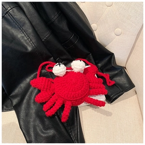 Detailed close-up of a red handmade crochet crab crossbody bag for kids on a dark background