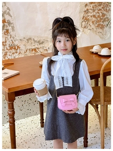 Pink mini crossbody bag with bow and gold chain strap worn by a young girl