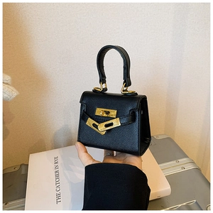 Détail d'un mini sac à main noir en cuir grainé avec fermoir rotatif métallique chic