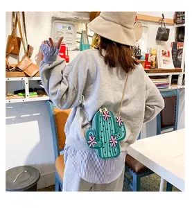 Detail of quirky cactus shaped crossbody bag with green dotted texture and pink flower