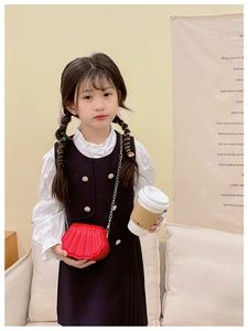 Détail du sac bandoulière rouge en forme de coquille avec chaîne dorée pour enfant