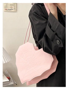 Sac à bandoulière rose en forme de cœur avec coutures en toile d'araignée sur modèle