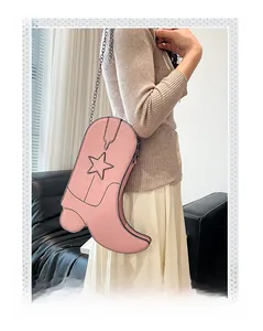 Close-up of pink denim boot-shaped crossbody bag with star stitching and black chain strap
