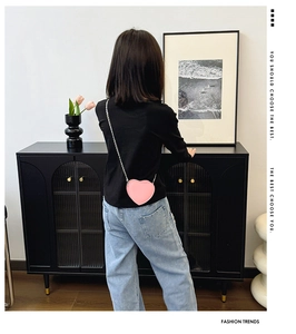 Vue arrière d'un enfant portant un sac bandoulière rose en forme de cœur en cuir PU