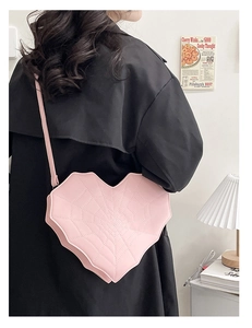 Sac bandoulière rose en forme de cœur avec texture toile d'araignée sur manteau noir