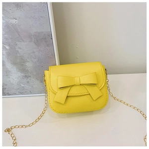 Close-up of a yellow mini PU leather girl bag with a cute bow and gold chain strap
