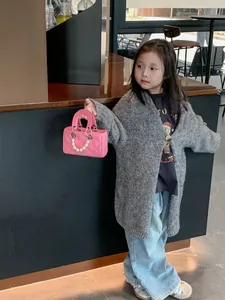 Pink quilted crossbody child bag with pearl handle shown on a child model in a cafe