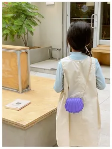 Photo lifestyle d'une fille portant un mini sac violet en forme de coquillage chic