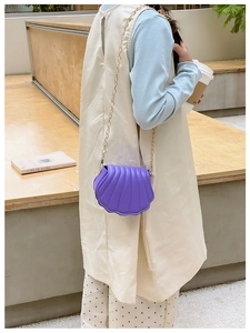 Détail du mini sac violet en forme de coquille avec chaîne dorée sur une tenue