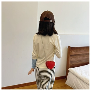 Détail d'un sac à bandoulière rouge en forme de cœur avec chaîne argentée