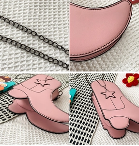 Detail showing pink boot-shaped bag with black star stitching and metal chain strap