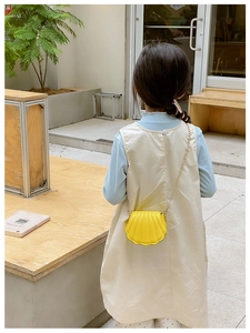 Enfant portant le mini sac bandoulière coquillage jaune vif avec sa chaîne dorée en extérieur