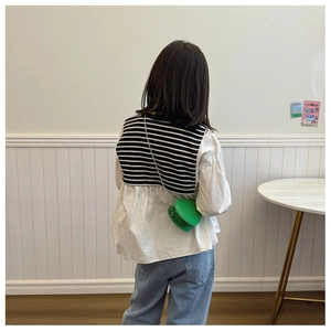 Vue arrière d'un enfant portant un sac vert en forme de cœur avec gilet rayé et jean
