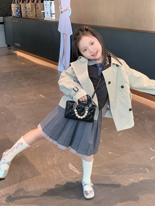 Kid's quilted shoulder bag with pearl handle shown with a stylish trench coat