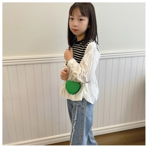 Sac bandoulière enfant vert en forme de cœur porté par un jeune mannequin