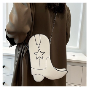 Detail showing white cowboy boot shaped crossbody bag with black star and chain strap
