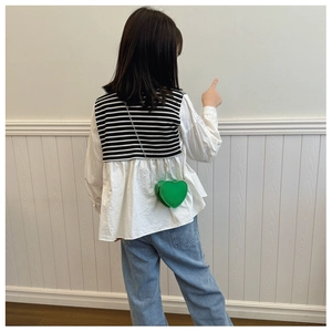 Détail d'une chemise rayée enfant avec un sac à bandoulière vert en forme de cœur