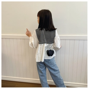 Détail d'un sac bandoulière cœur noir pour enfant avec chaîne et tenue en jean assortie