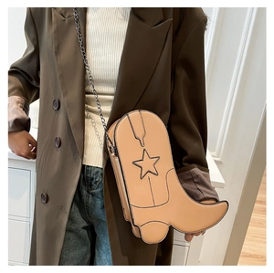 Close-up of khaki leather boot-shaped crossbody bag featuring star stitching and chain strap