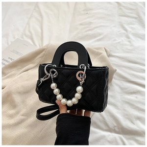 Detail of black quilted crossbody bag featuring a large pearl chain and silver clasp