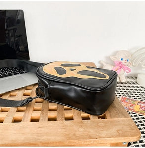 Detailed macro view of the reflective Ghostface mask motif on a black crossbody bag